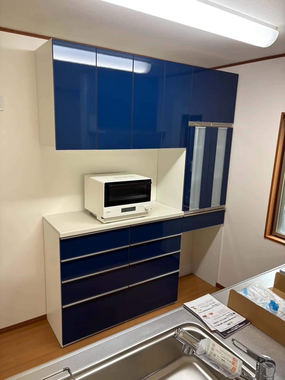 キッチンの背面に設置した、青い扉のカップボード